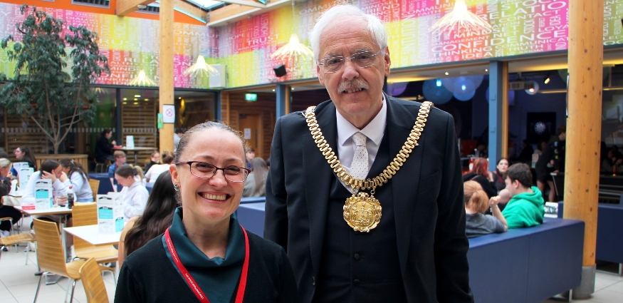 A male wearing mayoral chains standing next to a female.
